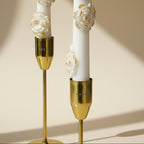 Decorative candles with gold holders and floral designs on a beige background
