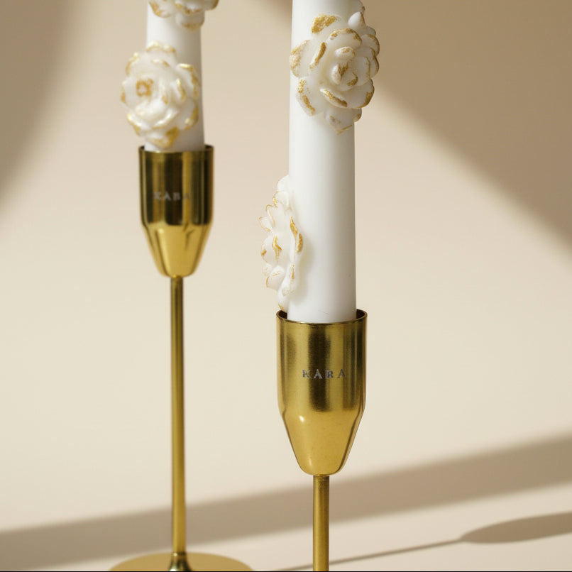Decorative candles with gold holders and floral designs on a beige background