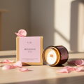 Kara Rose candle and packaging on a wooden surface with pink petals.