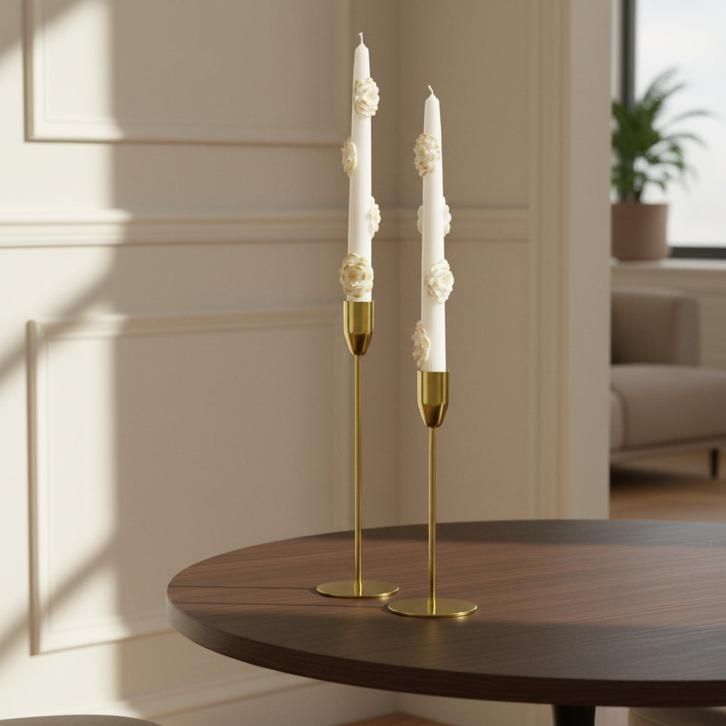 Two white taper candles with gold bases and decorative elements