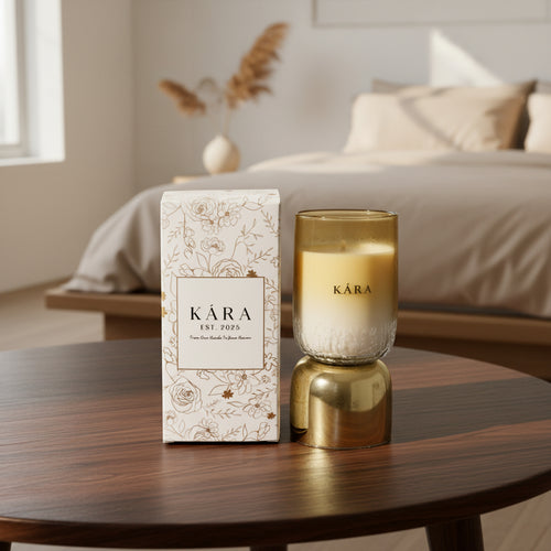 Kára candle and packaging on a wooden table with a bedroom in the background