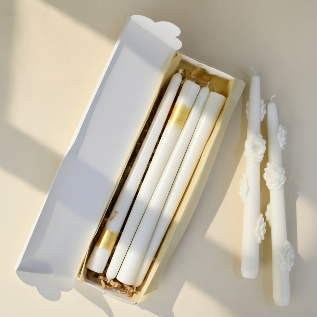 Set of white candles with floral designs on an ivory surface
