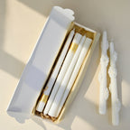 Set of white candles with floral designs on an ivory surface